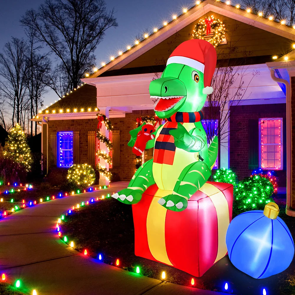 Inflatable dinosaur with a Santa hat on a gift box in front of a house decorated with Christmas lights.