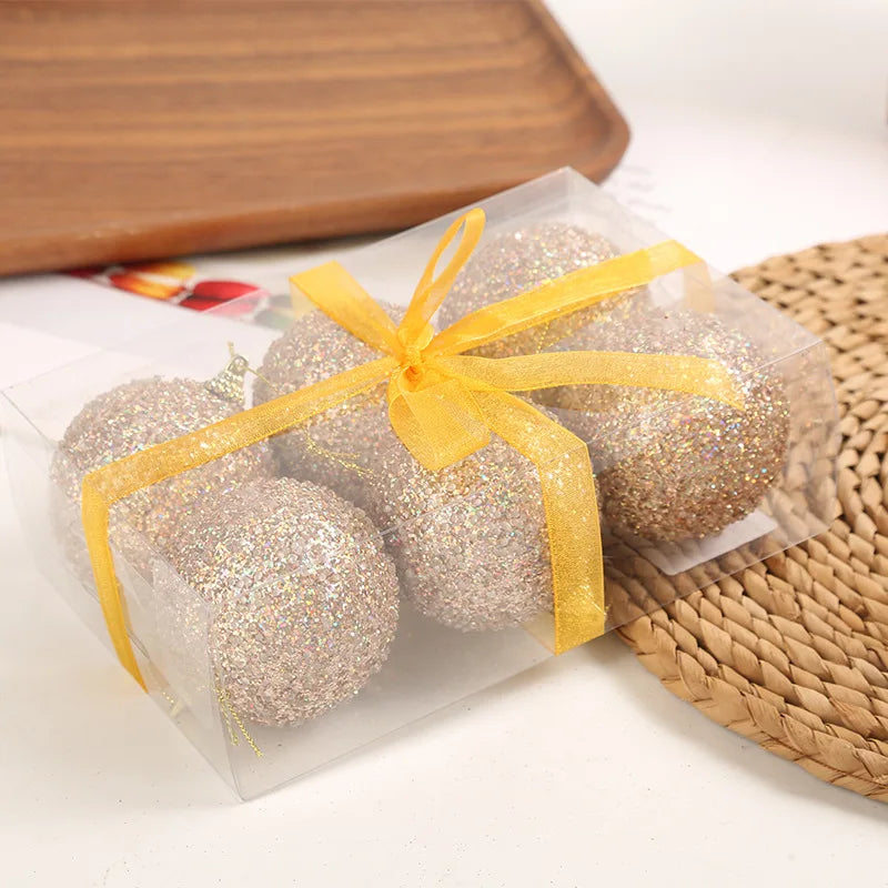 Six glittery balls tied with a yellow ribbon in a clear package on a wooden surface.