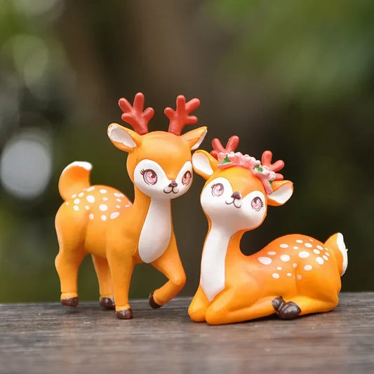 Two cute deer figurines on a wooden surface with a blurred natural background