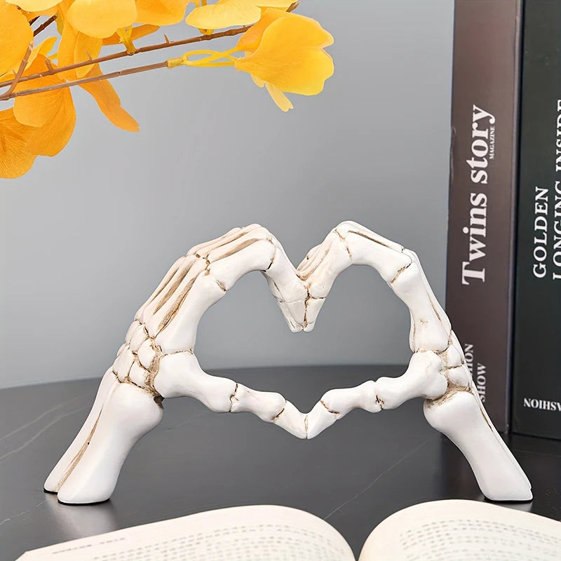 Decorative sculpture of skeletal hands forming a heart shape in white on a dark surface.
