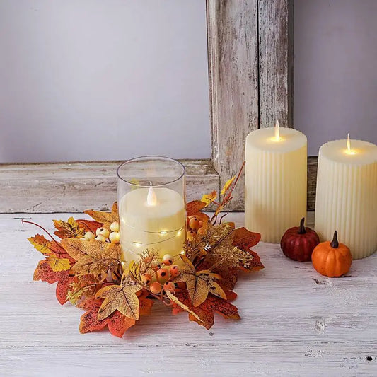 Decorative autumn candle arrangement featuring cream pillar candles, orange leaves, berries, and mini pumpkins on a rustic wooden surface.