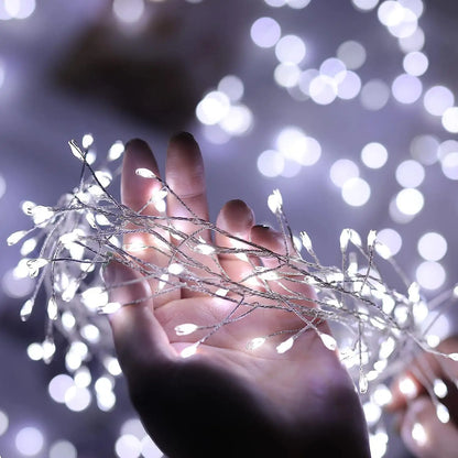 A hand gently holding cool white fairy firecracker lights with a soft bokeh background, creating a magical winter glow and cosy festive atmosphere.