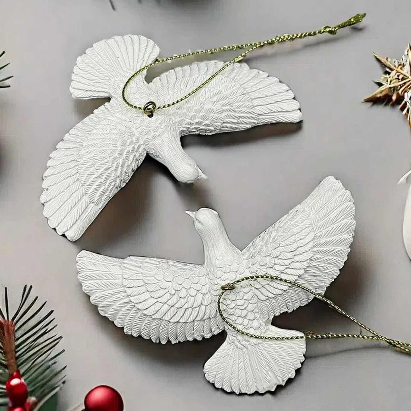 White dove-shaped ornaments on a gray surface with Christmas decorations.