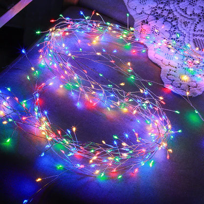 A string of multicoloured fairy firecracker lights glowing on a dark surface, creating a festive, cheerful atmosphere with soft reflections of red, blue, green, and yellow light.